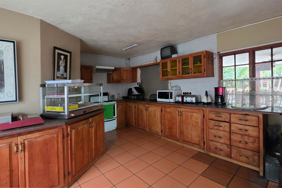 A dated kitchen featuring extensive wooden cabinetry, tiled flooring, and a built-in stove, offering significant potential for a modern renovation.