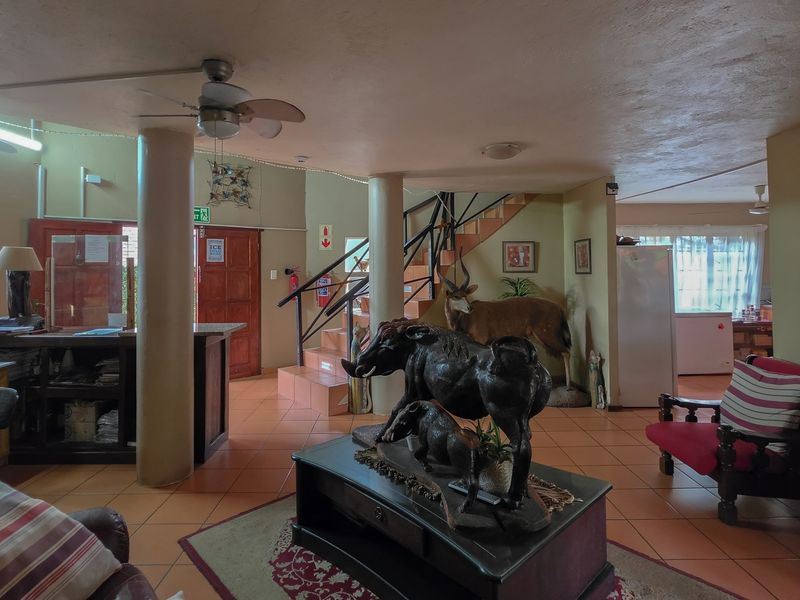 Spacious open-plan living area featuring structural columns, tiled flooring, and a central staircase, offering a versatile layout for various living arrangements.