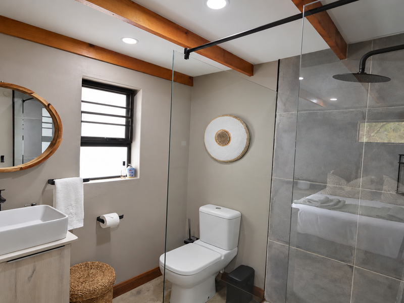 Modern bathroom featuring a vessel sink on a vanity, a glass-enclosed walk-in shower with a rain shower head, and exposed timber ceiling beams.