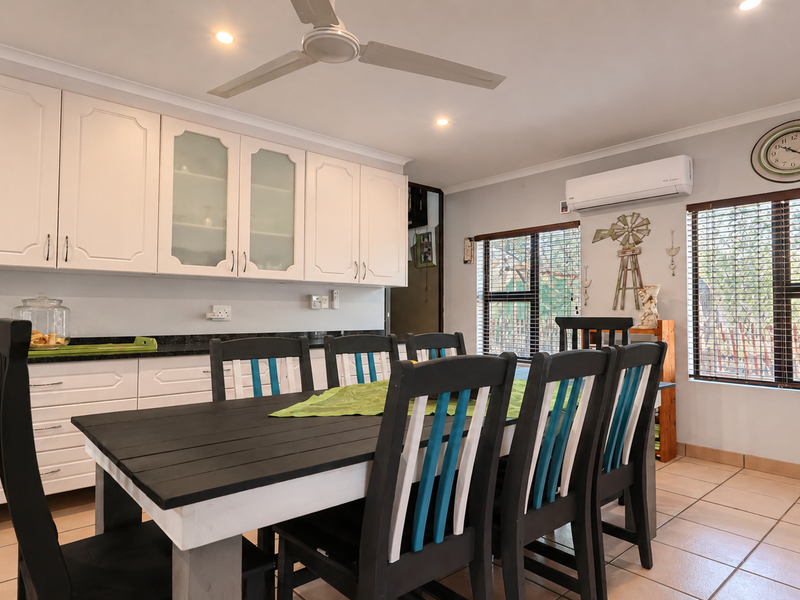 Open-plan dining area featuring tiled flooring, ceiling fan, split-system air conditioning, and built-in cabinetry with granite countertops.