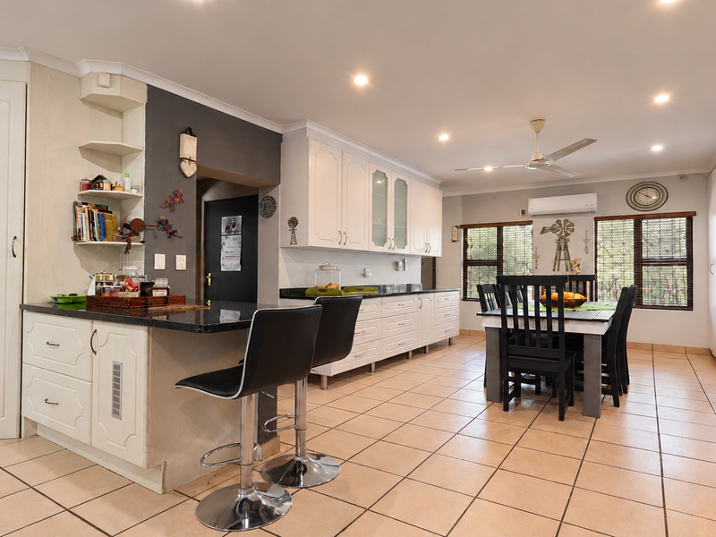 Spacious open-plan kitchen and dining area featuring tiled flooring, ample cabinetry, granite countertops, and integrated climate control.