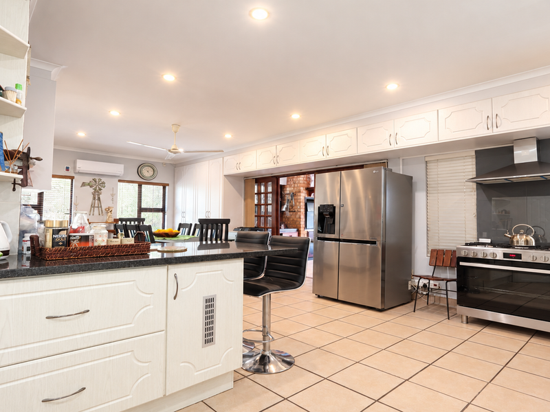 Spacious kitchen featuring granite countertops, ample built-in cabinetry, stainless steel gas stove with extractor fan, and tiled flooring throughout.