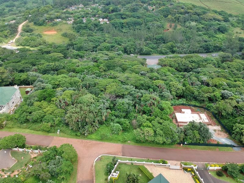 Aerial view of a residential vacant land plot featuring established vegetation and a partially constructed foundation, situated in a green, leafy neighborhood.