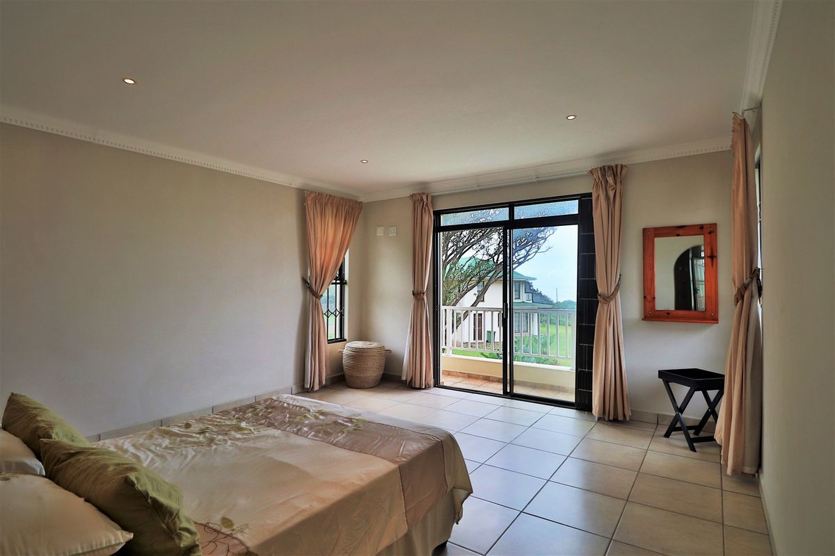 Spacious bedroom featuring tiled flooring, recessed ceiling lighting, and sliding glass doors opening onto a private balcony with scenic views.