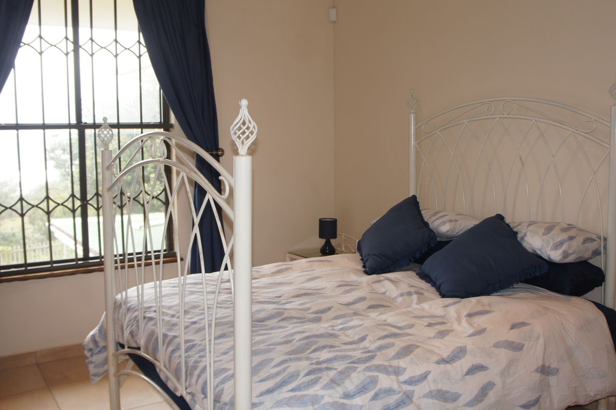 A bedroom featuring tiled flooring and a window fitted with a security gate, providing natural light and ventilation.