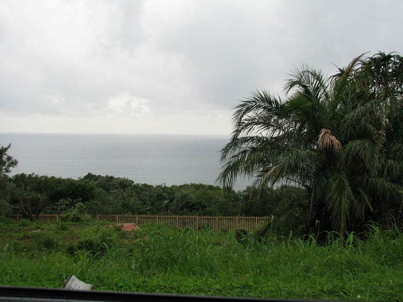 A scenic view of the ocean from the property, featuring natural vegetation and perimeter fencing.