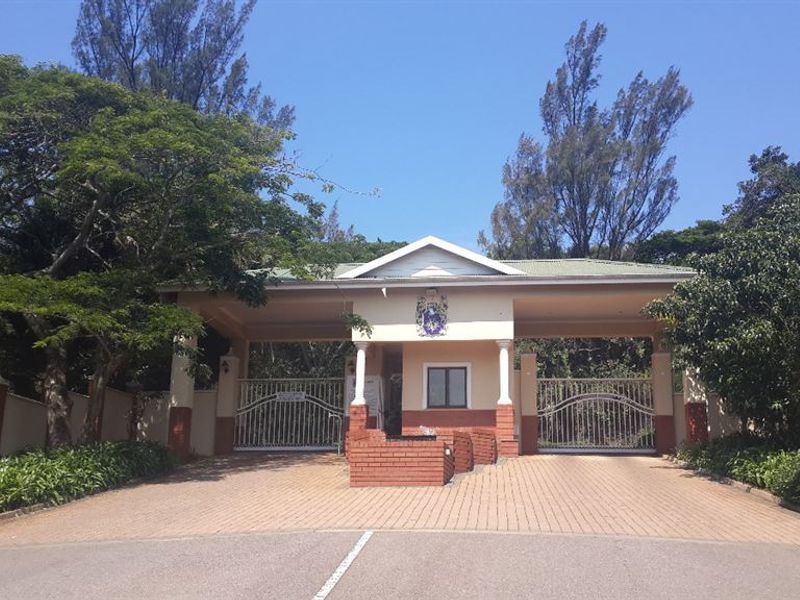 A well-maintained gated entrance to the residential property featuring a brick paved driveway and secure perimeter walling.