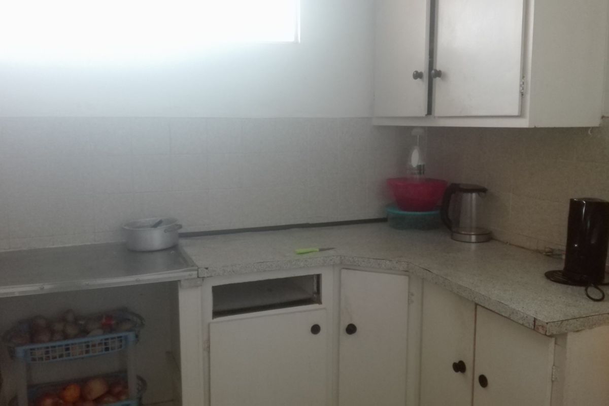 A functional kitchen area featuring white cabinetry, tiled splashbacks, and laminate countertops, providing a practical space for food preparation.