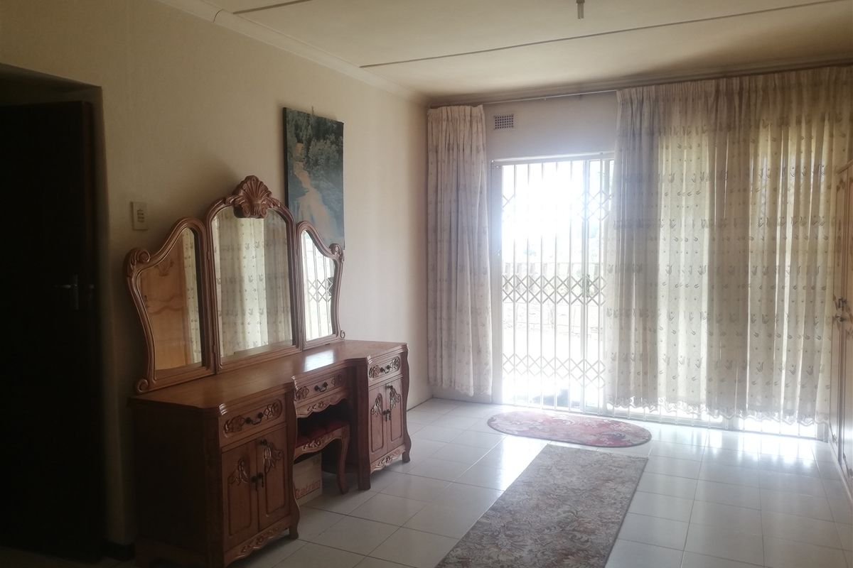 A bedroom featuring tiled flooring and a sliding glass door with security gate, providing access to the exterior.