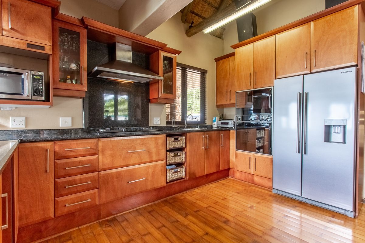 A well-appointed kitchen featuring warm wooden cabinetry, granite countertops, integrated appliances, and exposed timber ceiling beams, offering a classic and functional cooking space.