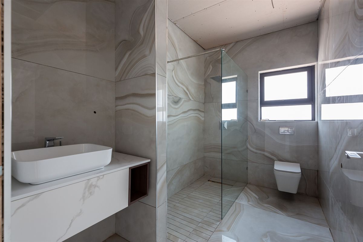Modern bathroom featuring large-format marble-look wall and floor tiles, a floating vanity, a glass-enclosed walk-in shower, and a wall-mounted toilet.