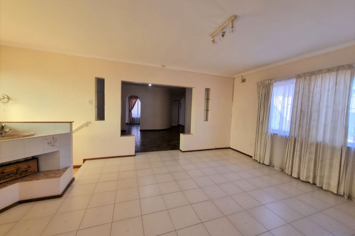 Spacious living area featuring tiled flooring, built-in display niches, and an open-plan layout leading to an adjacent room.