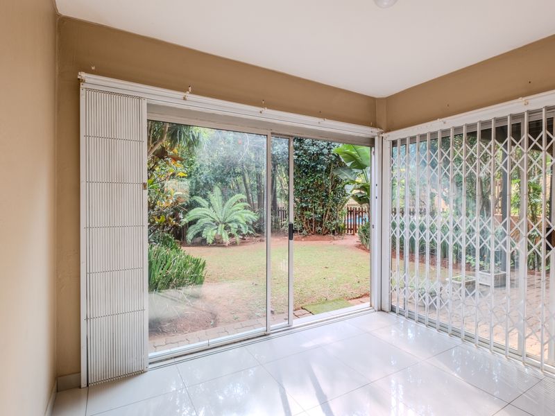Bright living area featuring large sliding glass doors with security gates, providing direct access to a private garden.