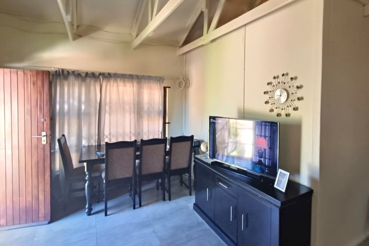 Living area featuring exposed roof trusses, tiled flooring, and a timber entrance door, providing a functional and open living space.