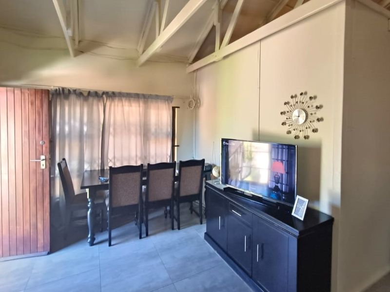 Living area featuring exposed roof trusses, tiled flooring, and a timber entrance door, providing a functional and open living space.