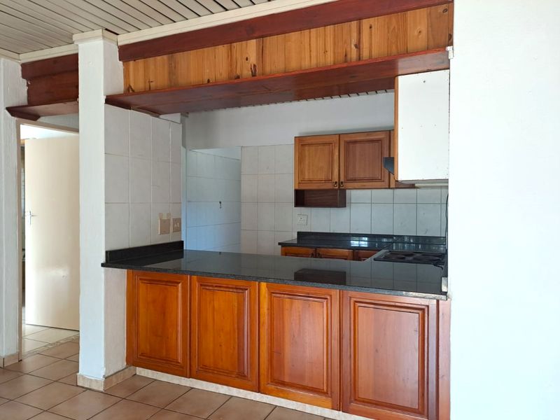 A functional kitchen featuring wooden cabinetry, granite countertops, and a tiled backsplash, offering a classic layout ready for modern updates.