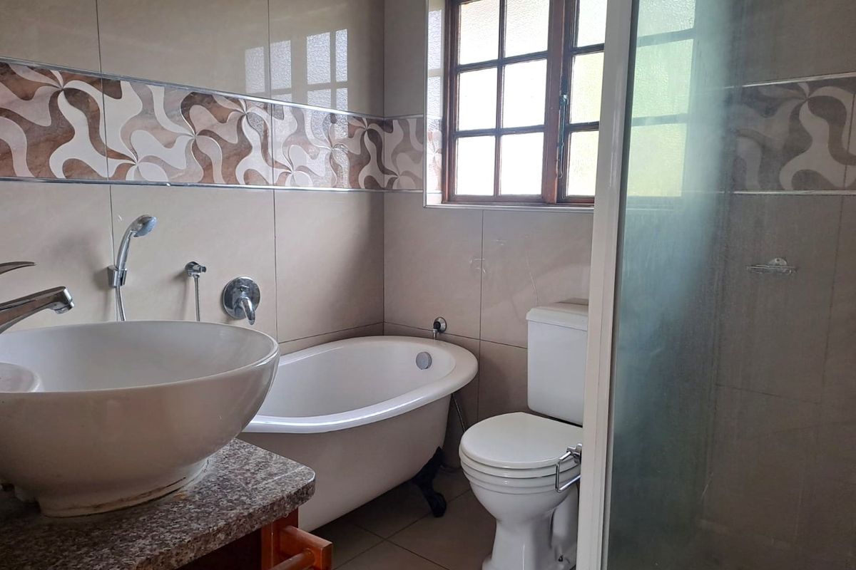 A functional bathroom featuring a freestanding bathtub, vessel sink on a granite vanity, toilet, and a separate shower enclosure with tiled finishes.