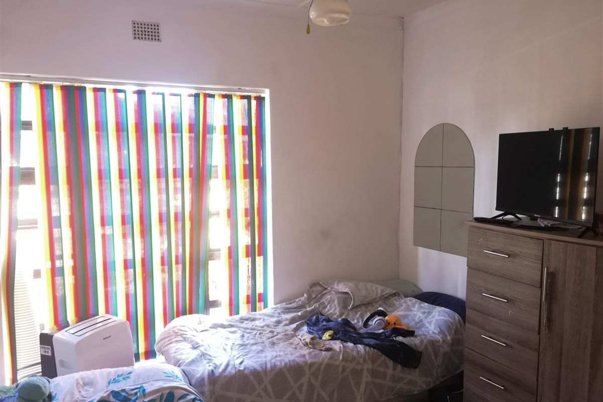 A standard bedroom featuring a ceiling fan and ventilation grille, providing a functional space with natural light.