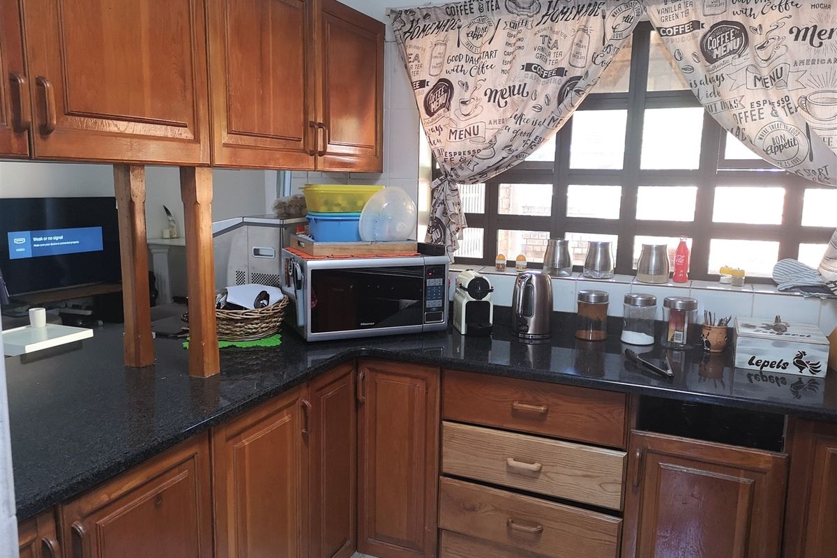 A functional kitchen featuring wooden cabinetry, dark granite countertops, and a tiled backsplash, offering a traditional aesthetic with potential for modernization.