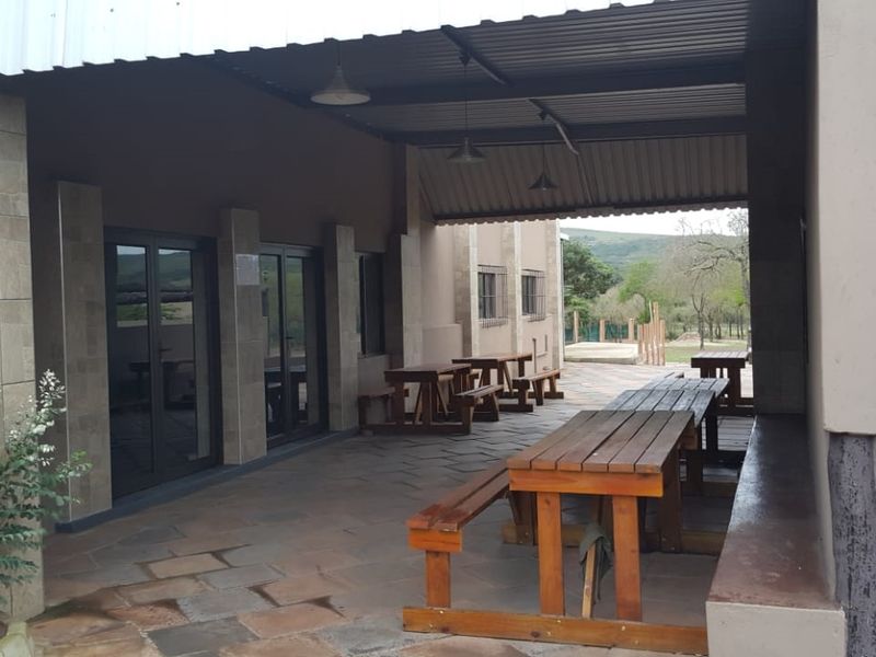 A spacious covered patio area featuring stone tile flooring, pendant lighting, and direct access to the interior through glass sliding doors.