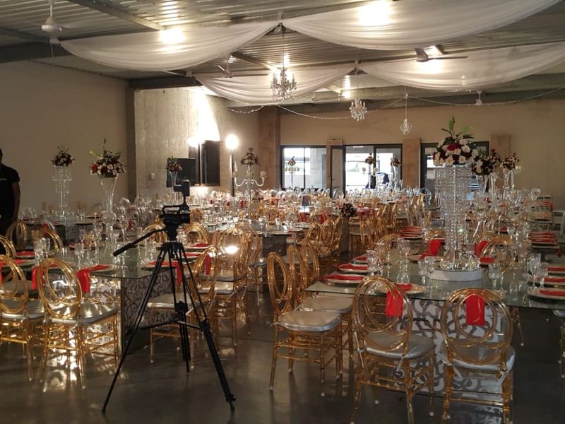 A spacious event hall featuring an industrial-style exposed metal ceiling, polished concrete floors, and large glass sliding doors leading to the exterior.