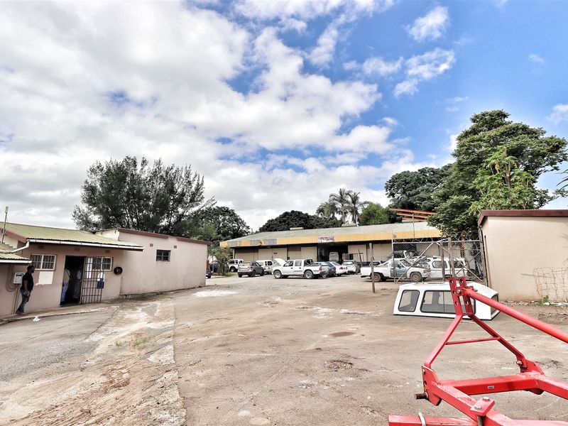 Exterior view of the office property featuring a large concrete yard area and industrial-style building structures.
