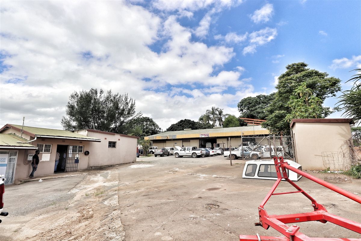 Exterior view of the office property featuring a large concrete yard area and industrial-style building structures.