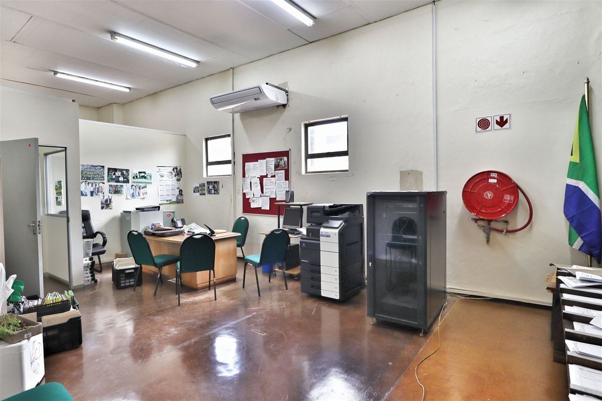 Functional office space featuring polished concrete floors, wall-mounted air conditioning, and integrated fire safety equipment, suitable for a professional work environment.