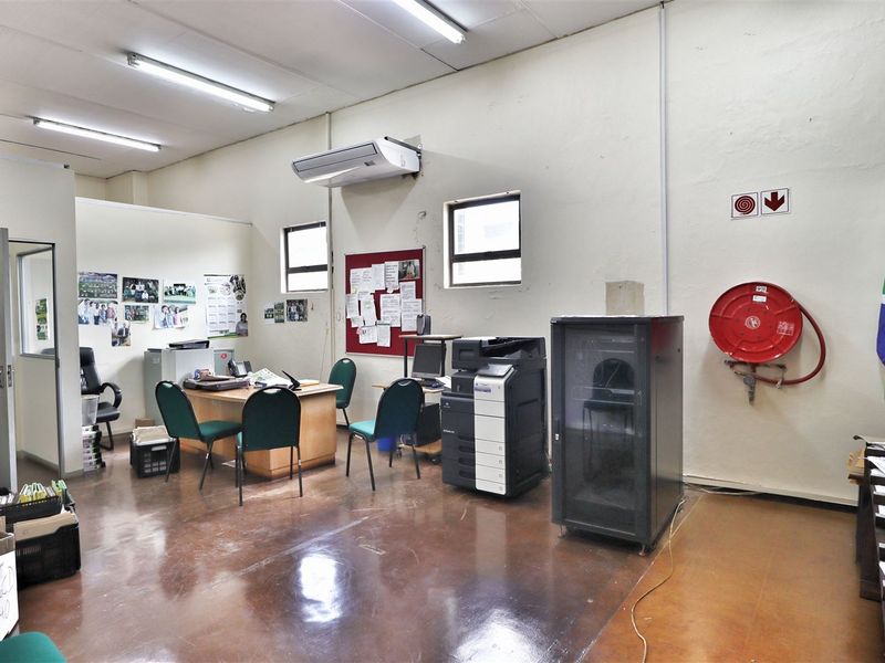 Functional office space featuring polished concrete floors, wall-mounted air conditioning, and integrated fire safety equipment, suitable for a professional work environment.