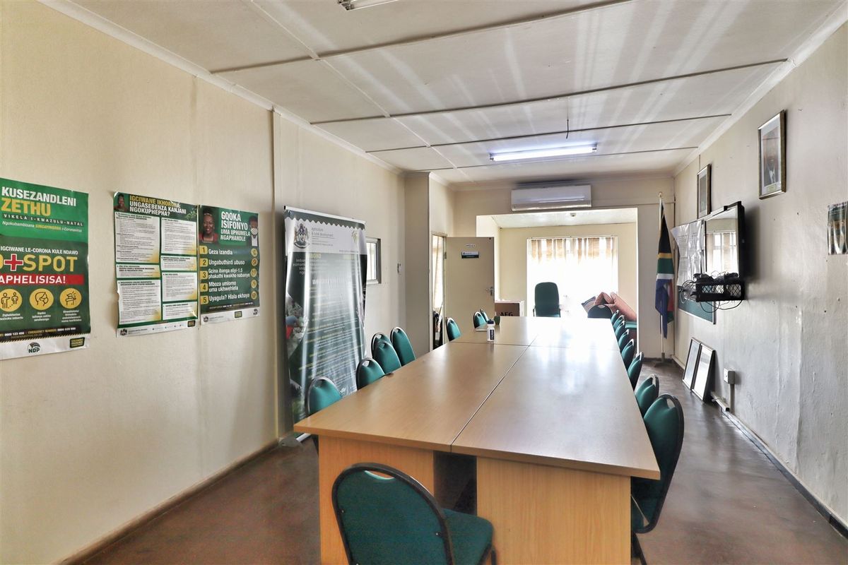 A functional office space featuring a long boardroom table, split-system air conditioning, and standard office lighting, suitable for meetings or collaborative work.
