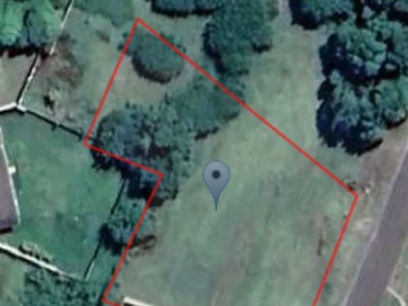 An aerial view of a vacant residential plot showing the property boundaries and surrounding vegetation.