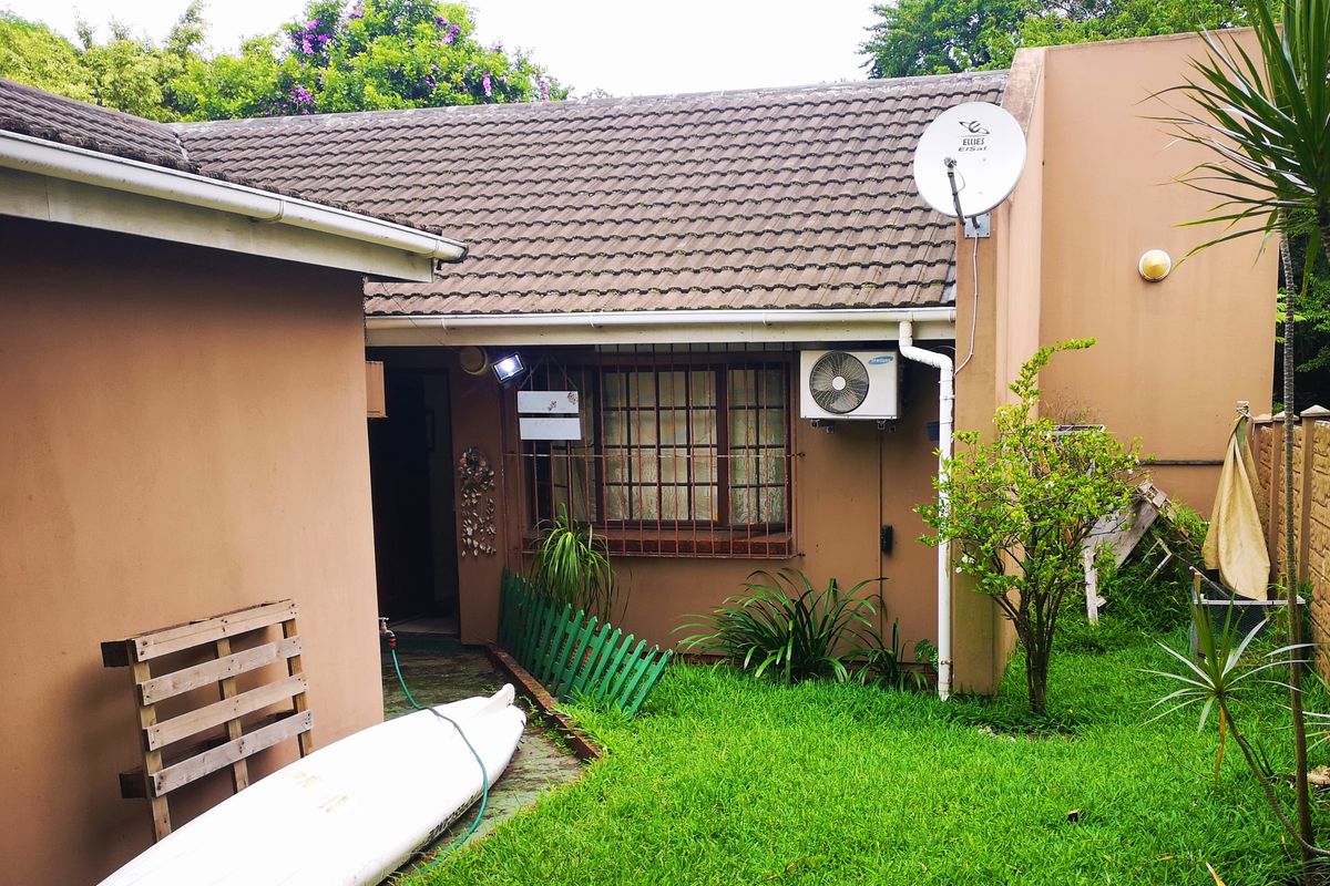 Rear exterior view of the townhouse featuring a tiled roof, security bars on windows, and an installed air conditioning unit.