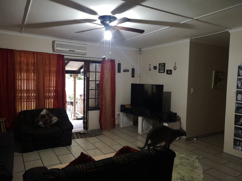 A living room featuring tiled flooring, a ceiling fan, and a split-system air conditioner, with direct access to an outdoor patio area.