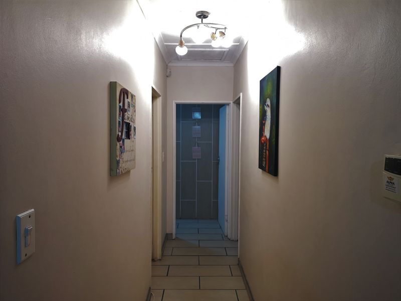 A functional hallway featuring tiled flooring and a central ceiling light fixture, providing access to adjacent rooms.