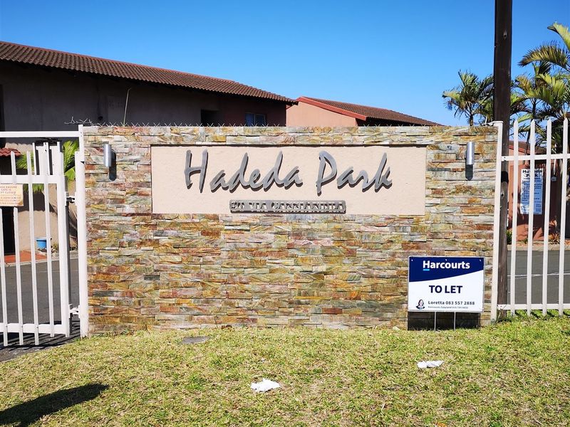 Entrance signage and security gate for Hadeda Park townhouse complex featuring stone cladding and perimeter security fencing.