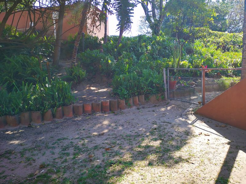 A sloped garden area featuring a small metal gate, retaining wall elements, and established greenery, providing a natural outdoor space for the townhouse.