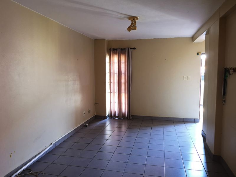 An empty living room featuring tiled flooring and a sliding glass door, providing a blank canvas for interior design updates.
