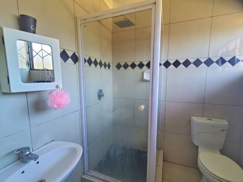 A functional bathroom featuring a shower enclosure, basin, and toilet with tiled finishes throughout.