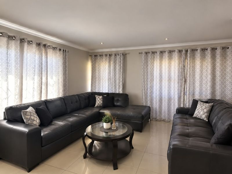 A well-maintained living room featuring neutral tiled flooring, recessed downlighting, and decorative curtain rails, creating a comfortable and bright living space.