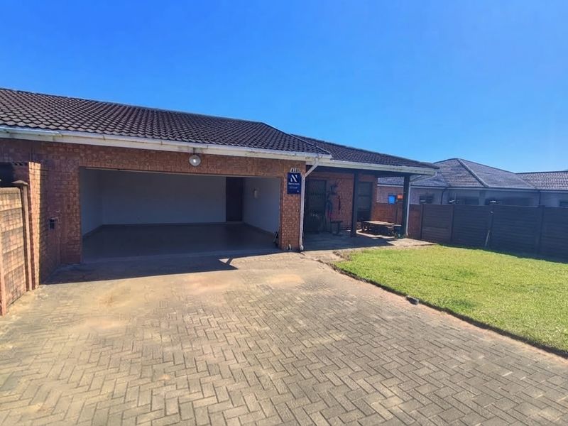 Front view of a duet property featuring a brick facade, tiled roof, paved driveway, double garage, and a small covered patio area.