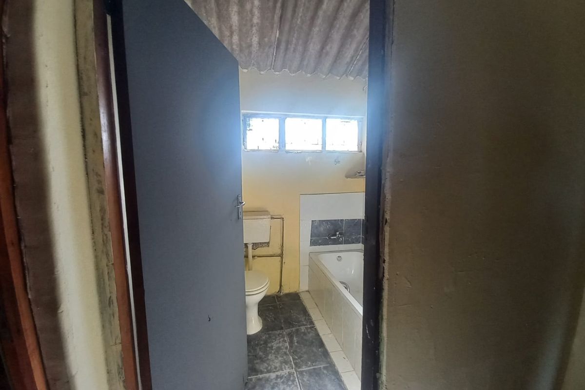 A dated bathroom featuring a bathtub, toilet, and basic finishes, requiring significant renovation and cosmetic updates.