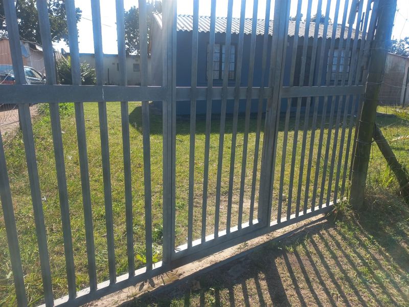 A view of the property exterior featuring a metal security gate and a front lawn area.
