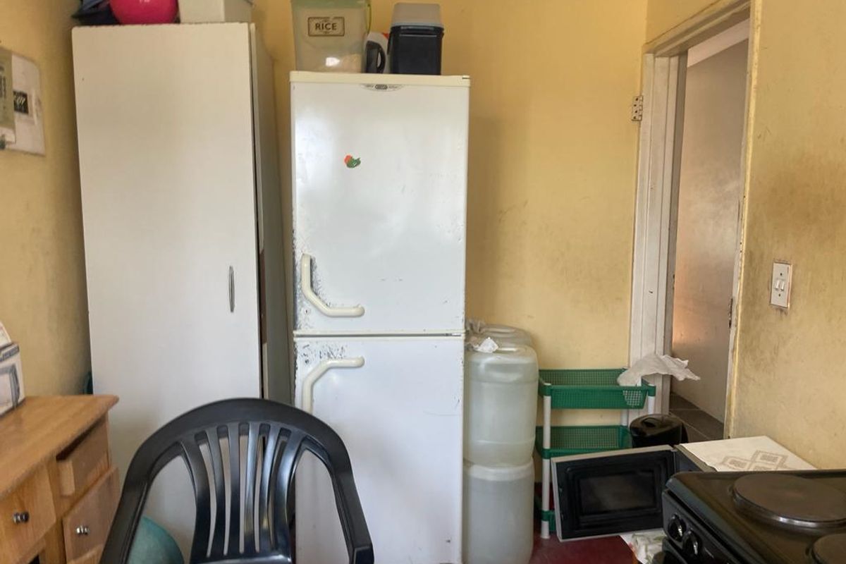 A small kitchen area featuring basic cabinetry and an electric stove, currently showing significant wear and requiring cosmetic updates to the wall finishes.