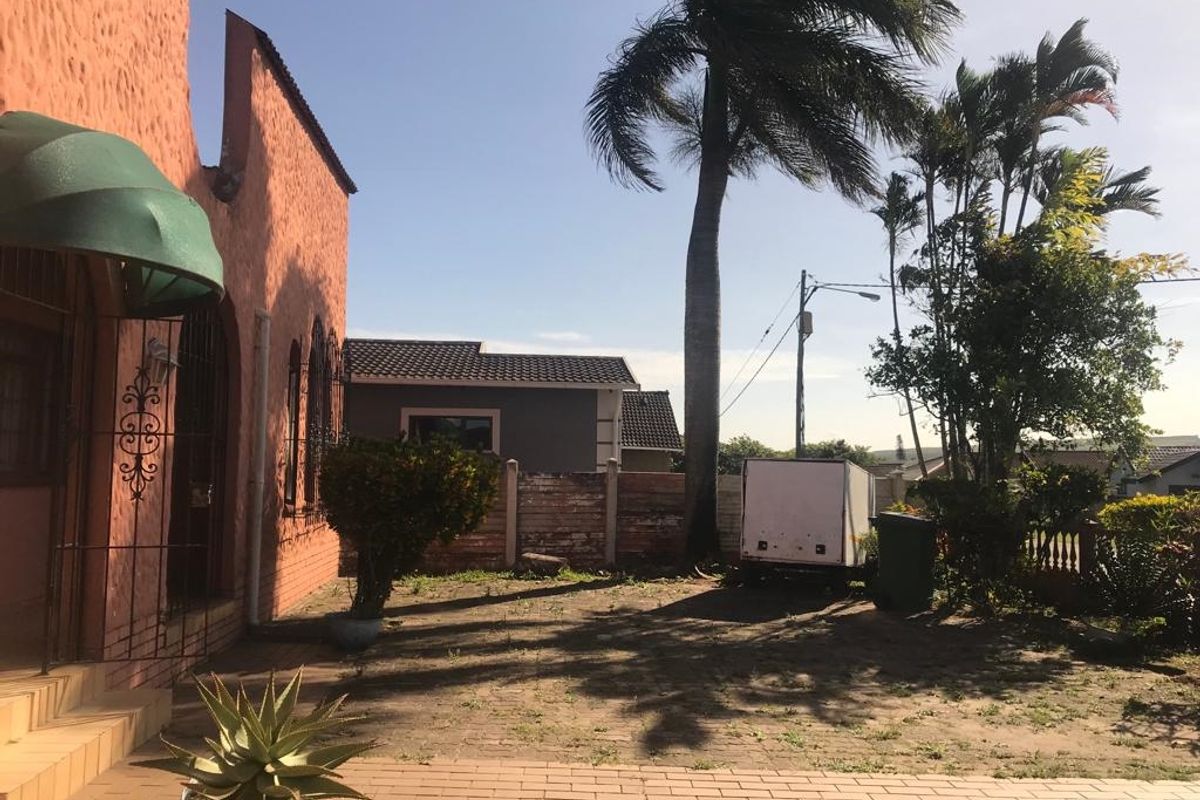 Rear exterior area featuring brick paving, a perimeter wall, and a covered entrance with a security gate.