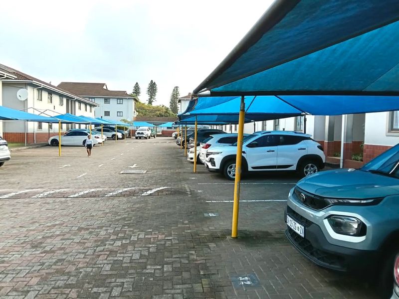 Outdoor parking area featuring paved surfaces and multiple shade cloth carports for vehicle protection.