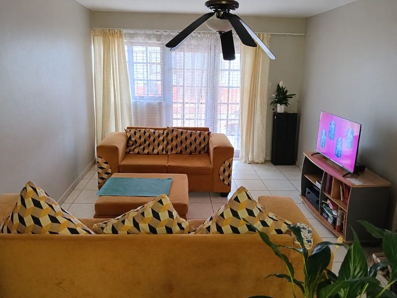 A comfortable living room featuring tiled flooring, a ceiling fan, and a sliding glass door that provides natural light.