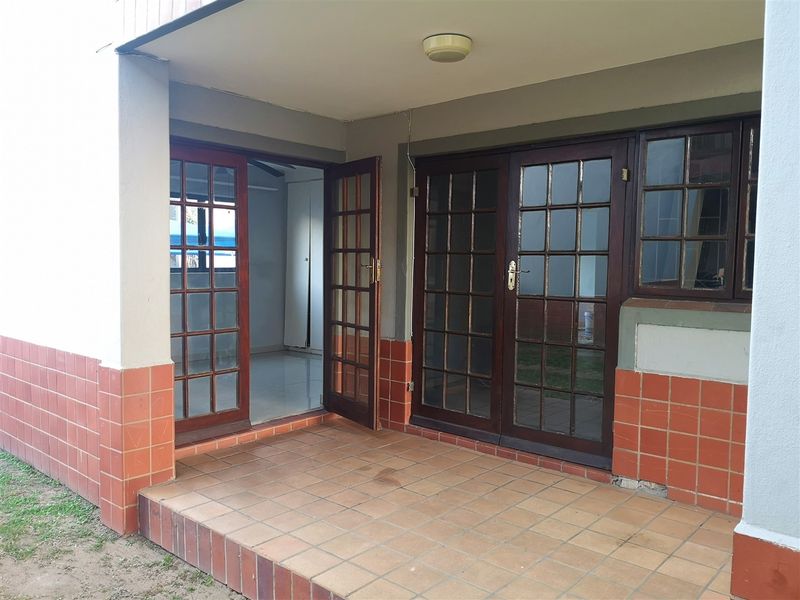 A covered patio area featuring tiled flooring and timber-framed glass doors providing access to the interior living space.