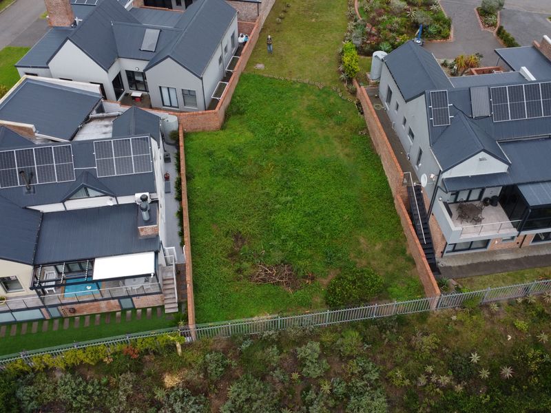 Aerial view of a vacant residential plot situated between two established modern homes in a secure estate.