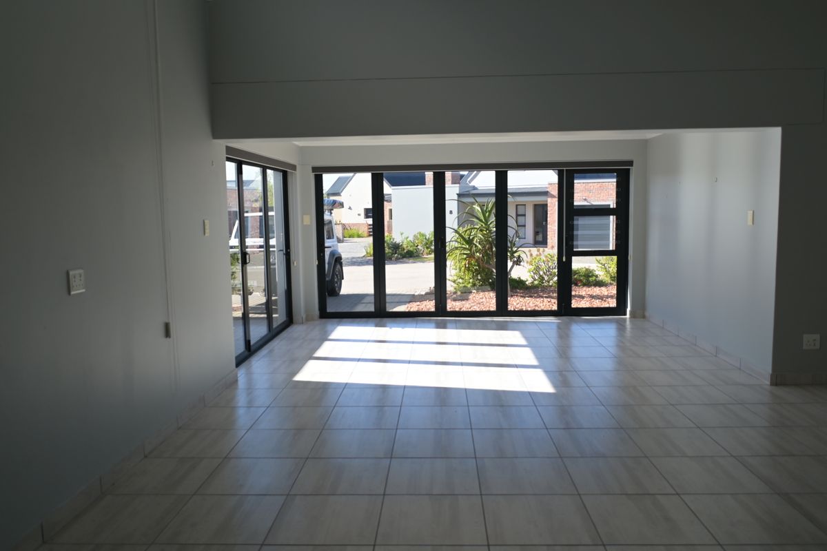 Spacious, empty living area featuring neutral tiled flooring and large aluminium stacker doors that provide abundant natural light and access to the exterior.