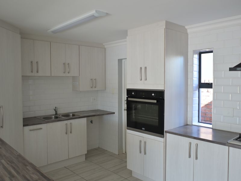 Modern kitchen featuring light wood-grain cabinetry, subway tile backsplash, dark laminate countertops, built-in oven, gas hob, and extractor fan.